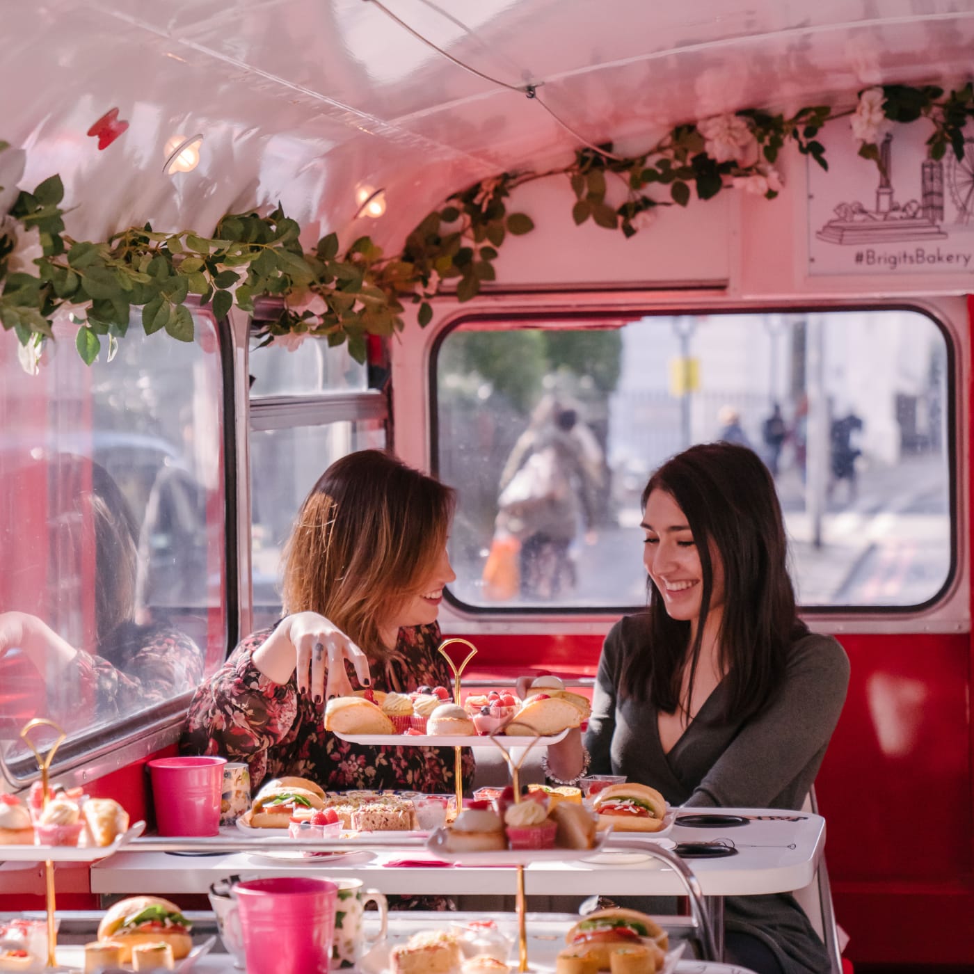 two women enjoying afternoon tea on a London bus